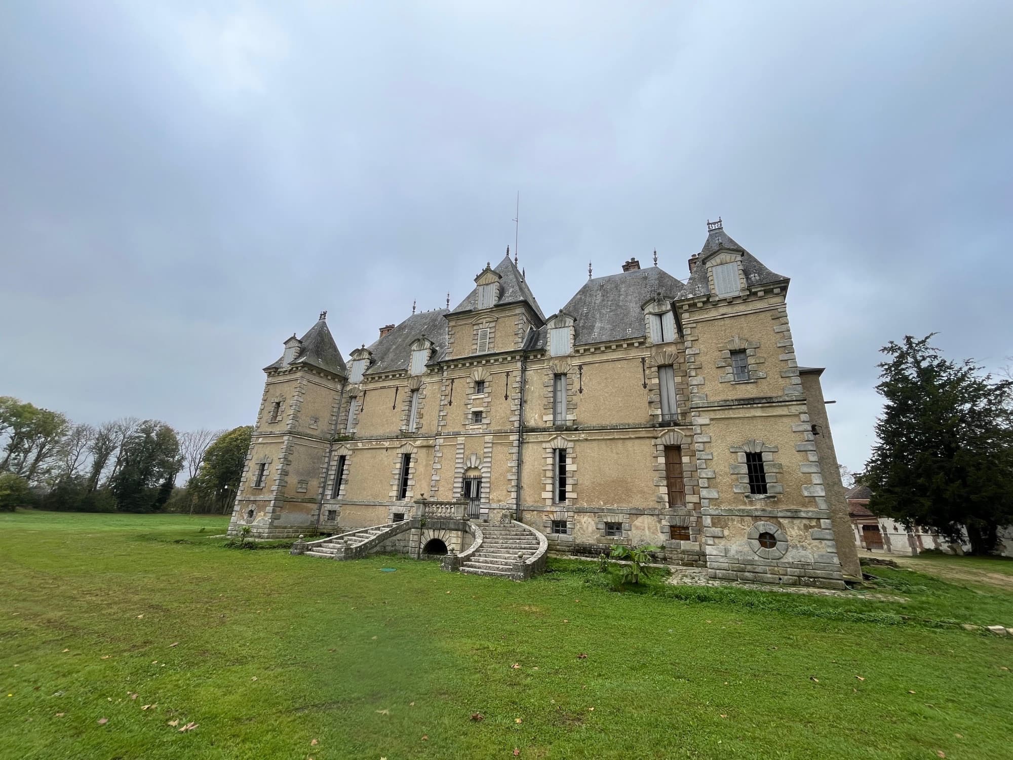 Façade arrière du château de Motteux et son escalier en fer à cheval, vue depuis la pelouse du parc