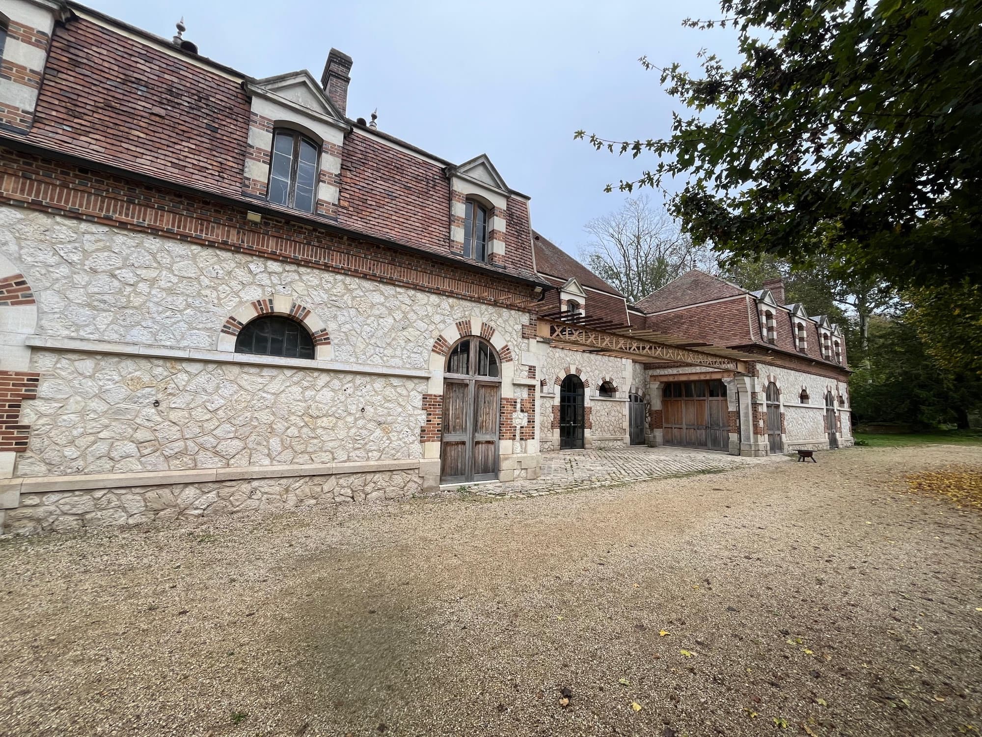 Anciennes écuries en pierre et brique du château de Motteux bordant la cour en gravier