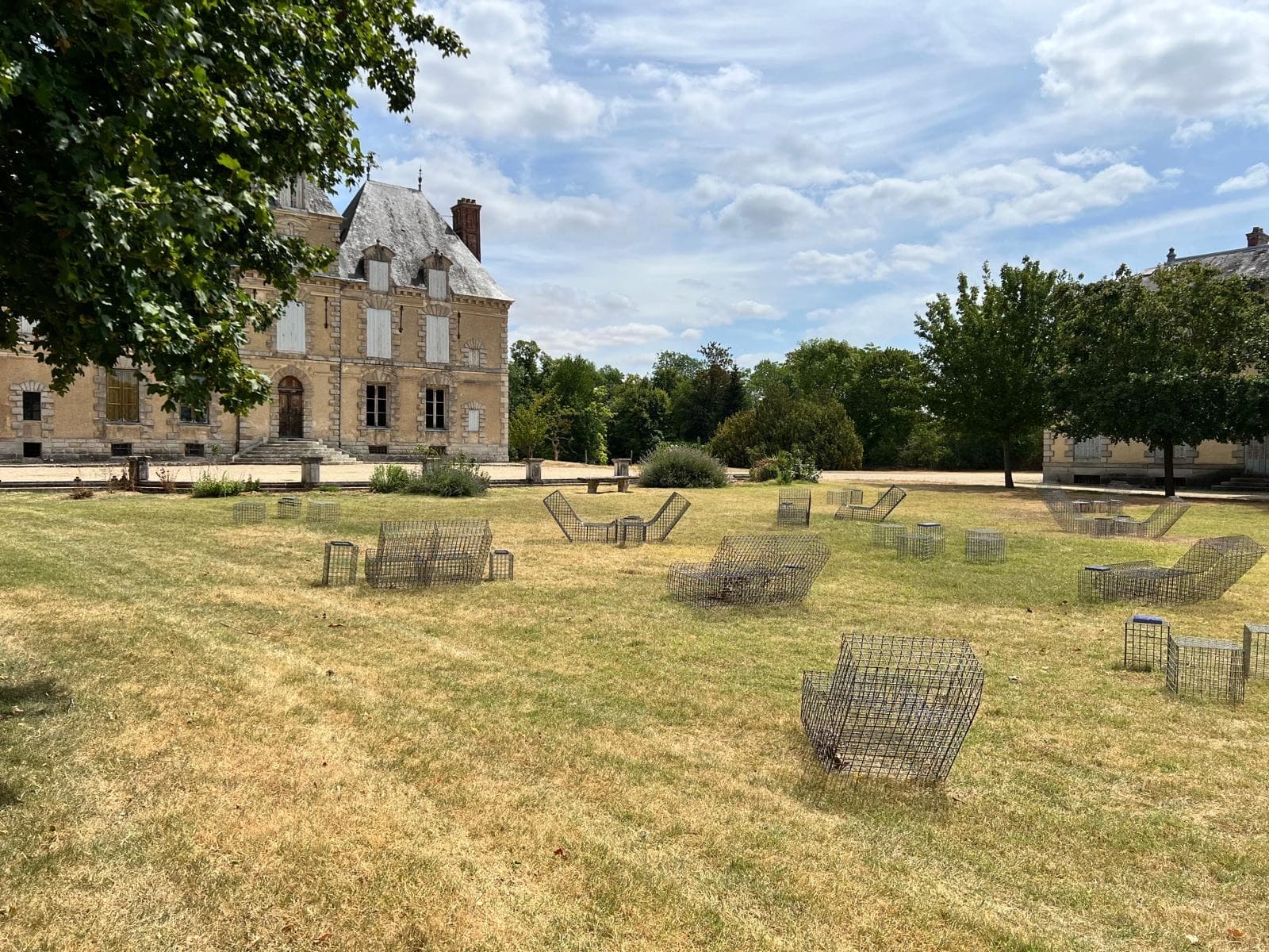Pelouse du parc du château de Motteux avec salons de jardin en métal devant la façade Renaissance