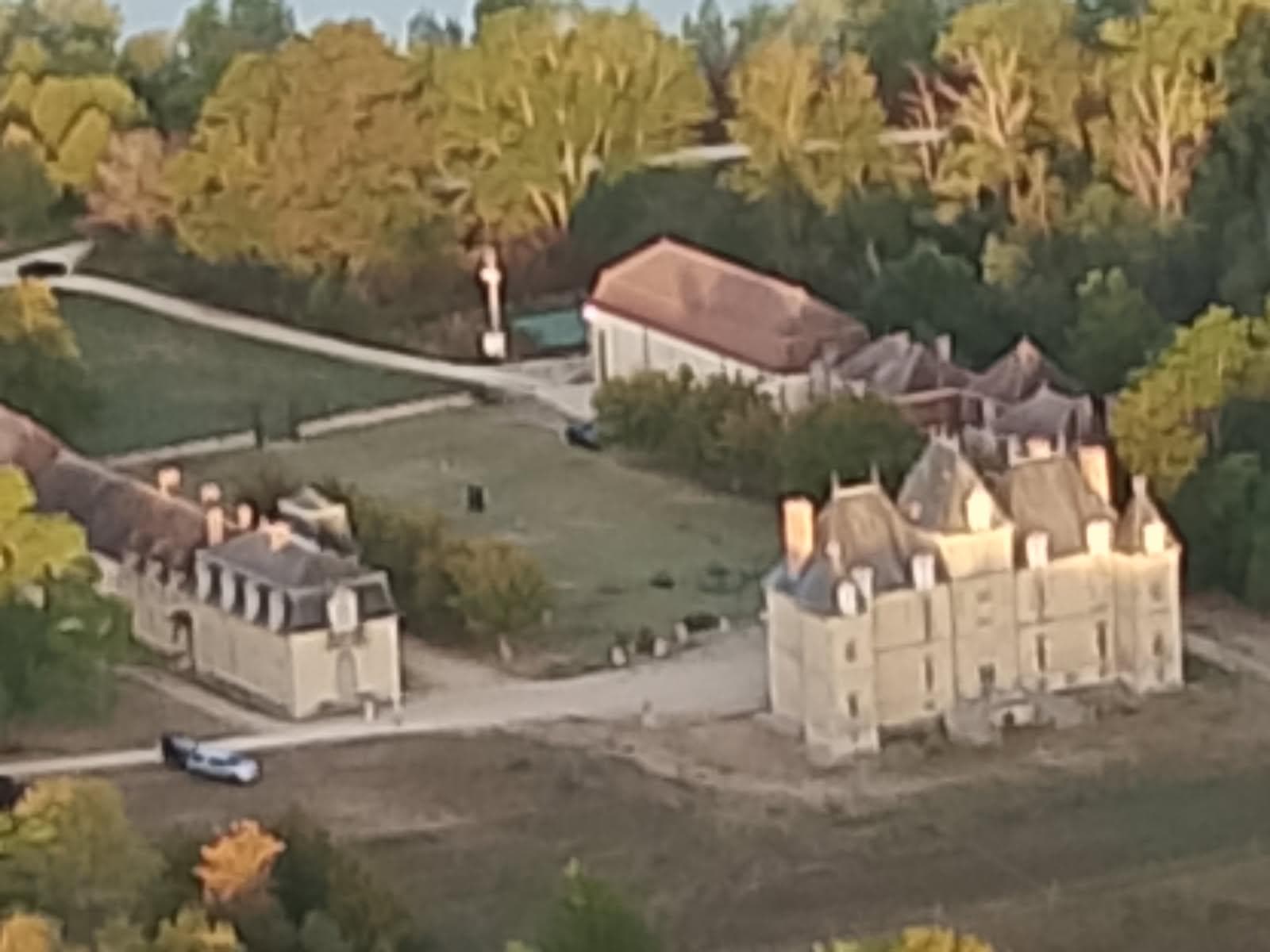 Vue aérienne du château de Motteux, de ses communs et de la grange, au cœur du parc boisé