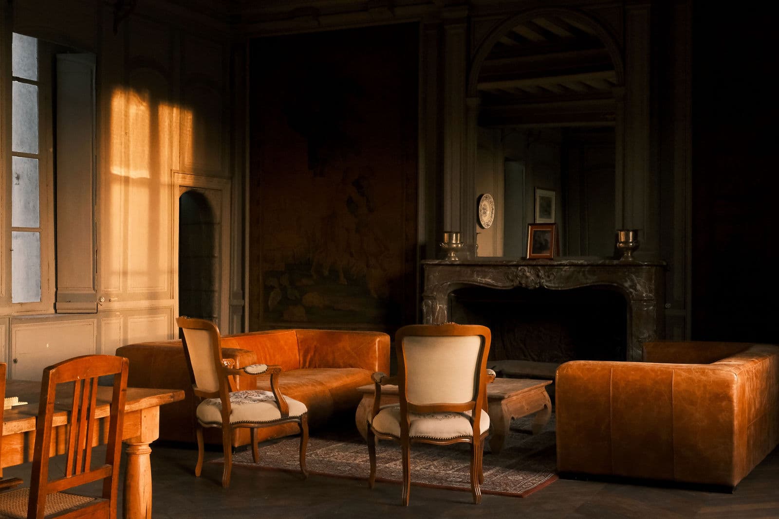 Salon lambrissé du château de Motteux : tapisserie ancienne, cheminée de marbre et canapés de cuir