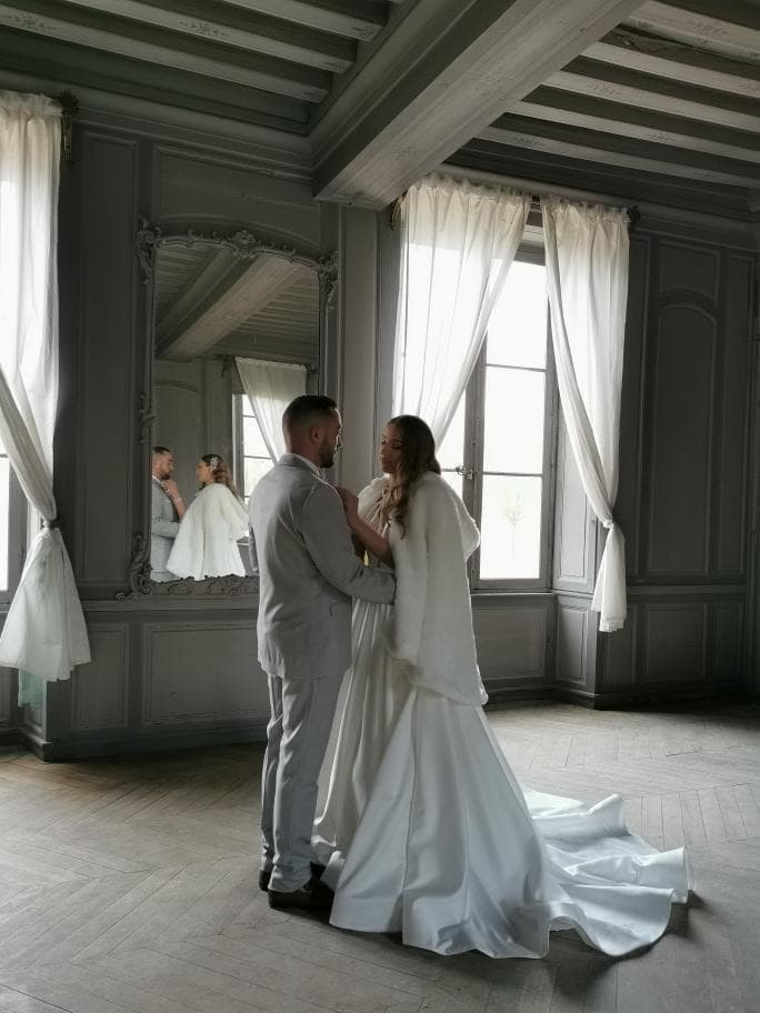 Mariés se reflétant dans le grand miroir doré d’un salon de réception du château de Motteux