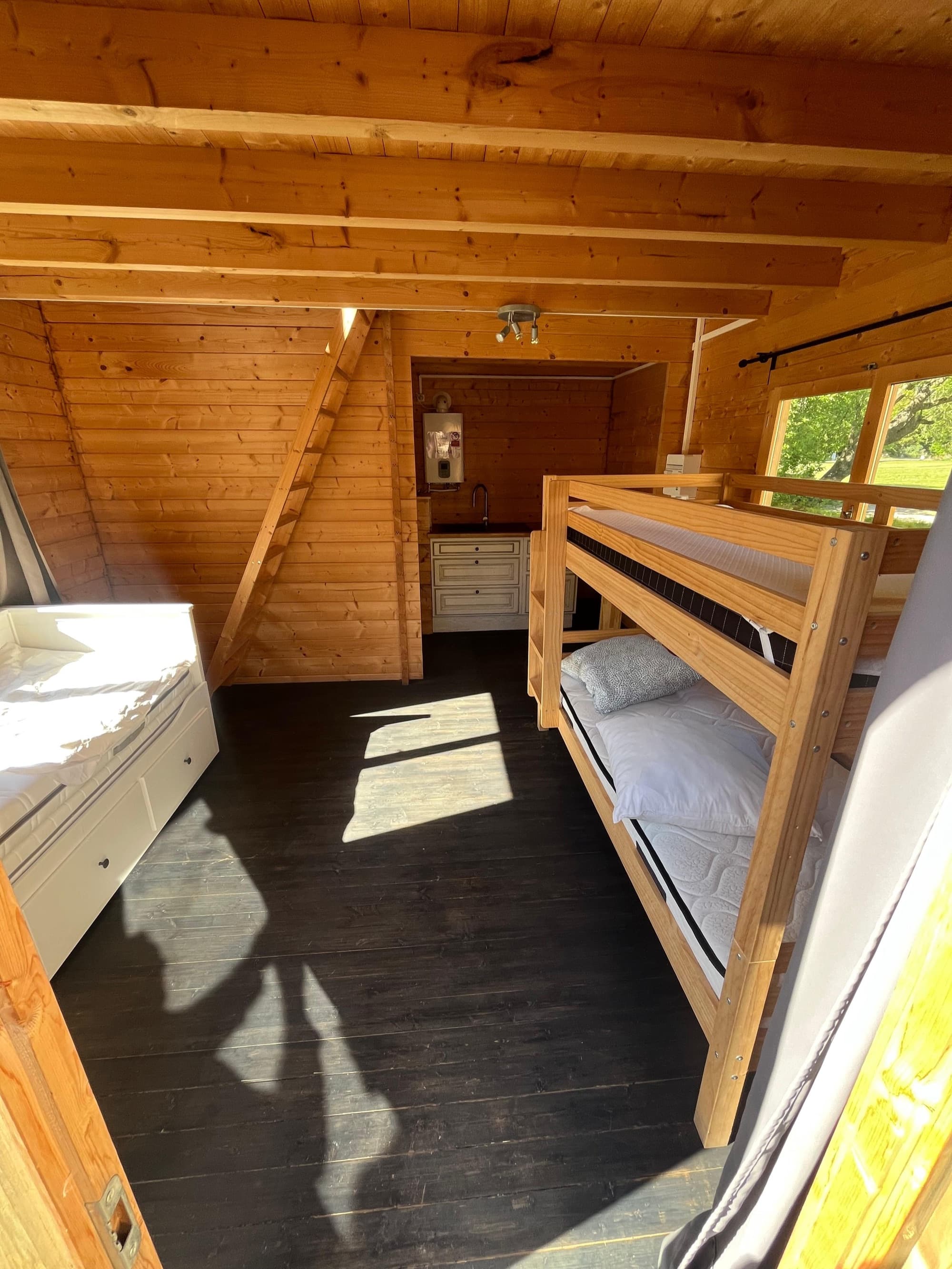 Intérieur en bois d’un chalet d’hébergement au château de Motteux, lits superposés et mezzanine