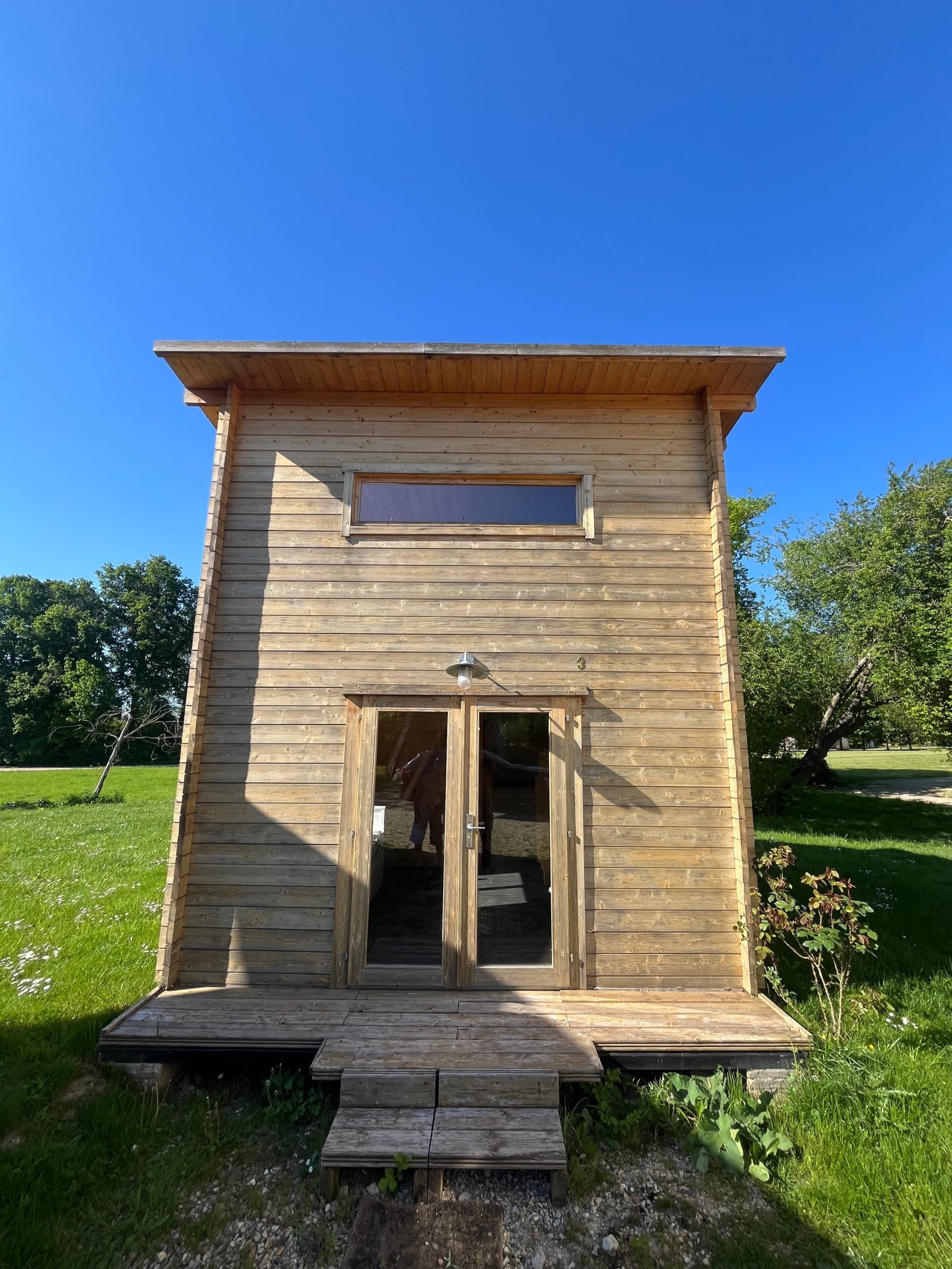 Chalet en bois pour les invités dans le parc du château de Motteux, sous un ciel bleu d’été