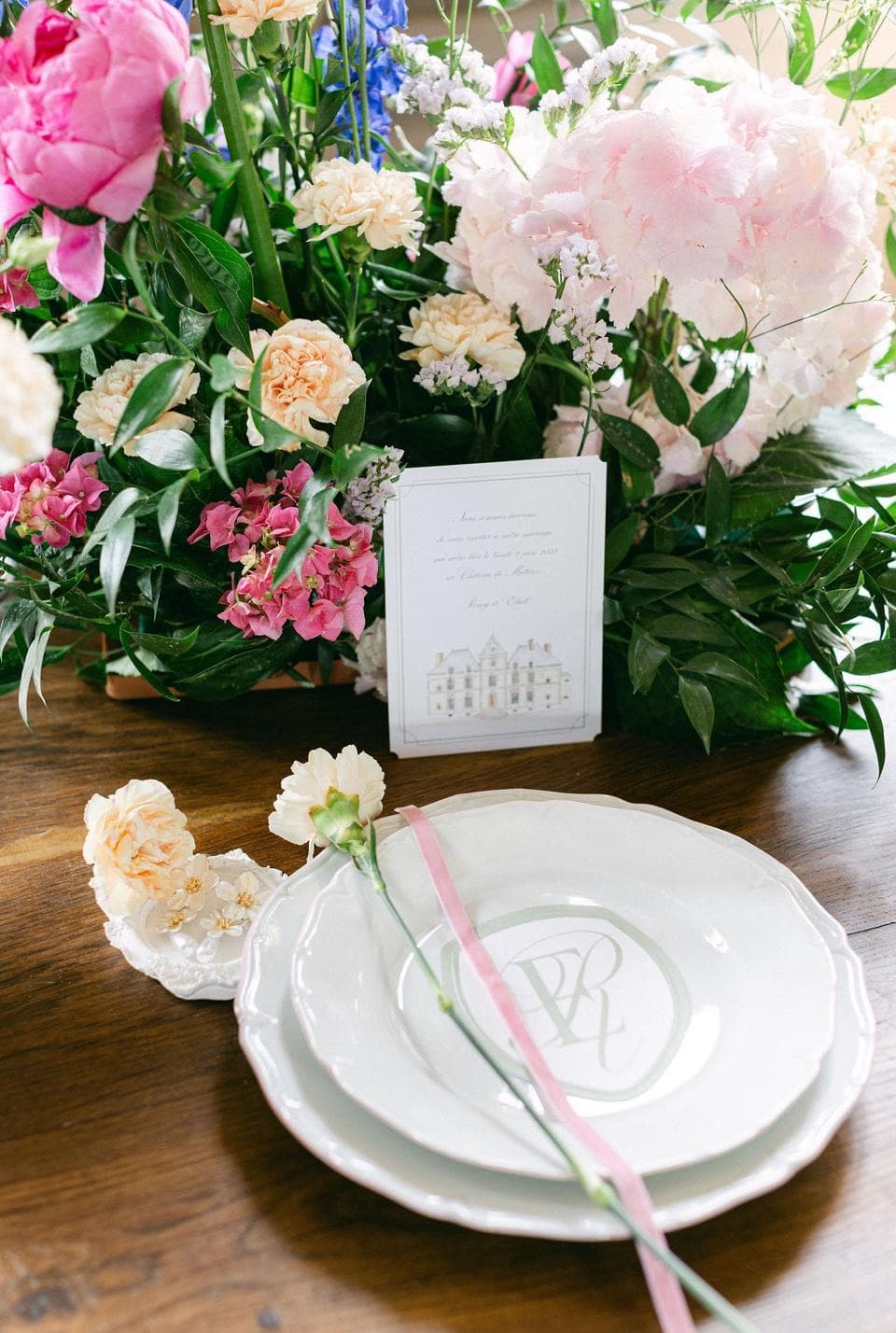 Table de réception raffinée au château de Motteux : vaisselle monogrammée et composition florale pastel