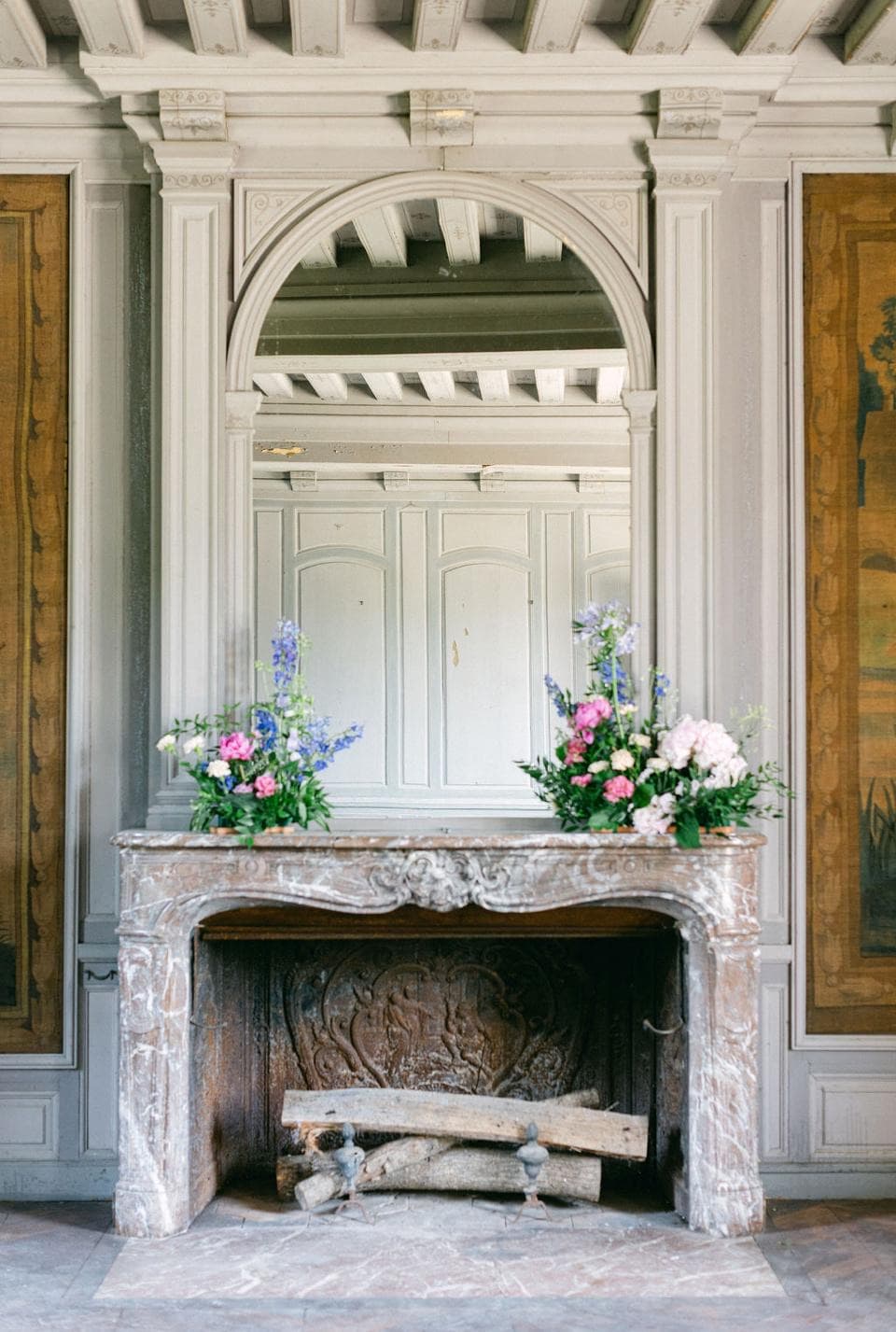 Cheminée en marbre et bouquets champêtres dans un salon du château de Motteux