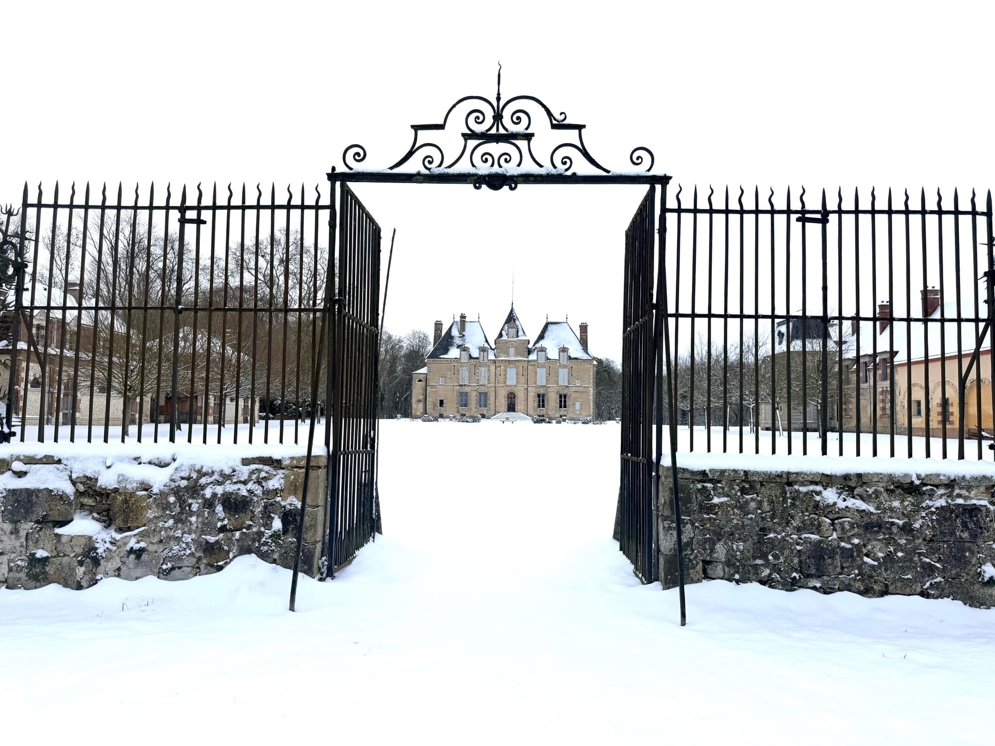 Grille en fer forgé du château de Motteux ouvrant sur le parc enneigé