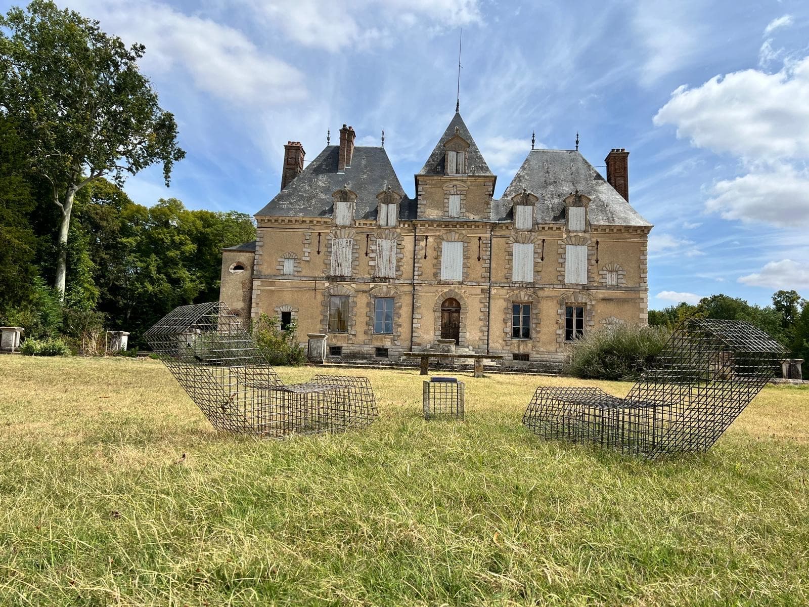 Vue frontale de la façade Renaissance du château de Motteux et transats design sur la pelouse du parc