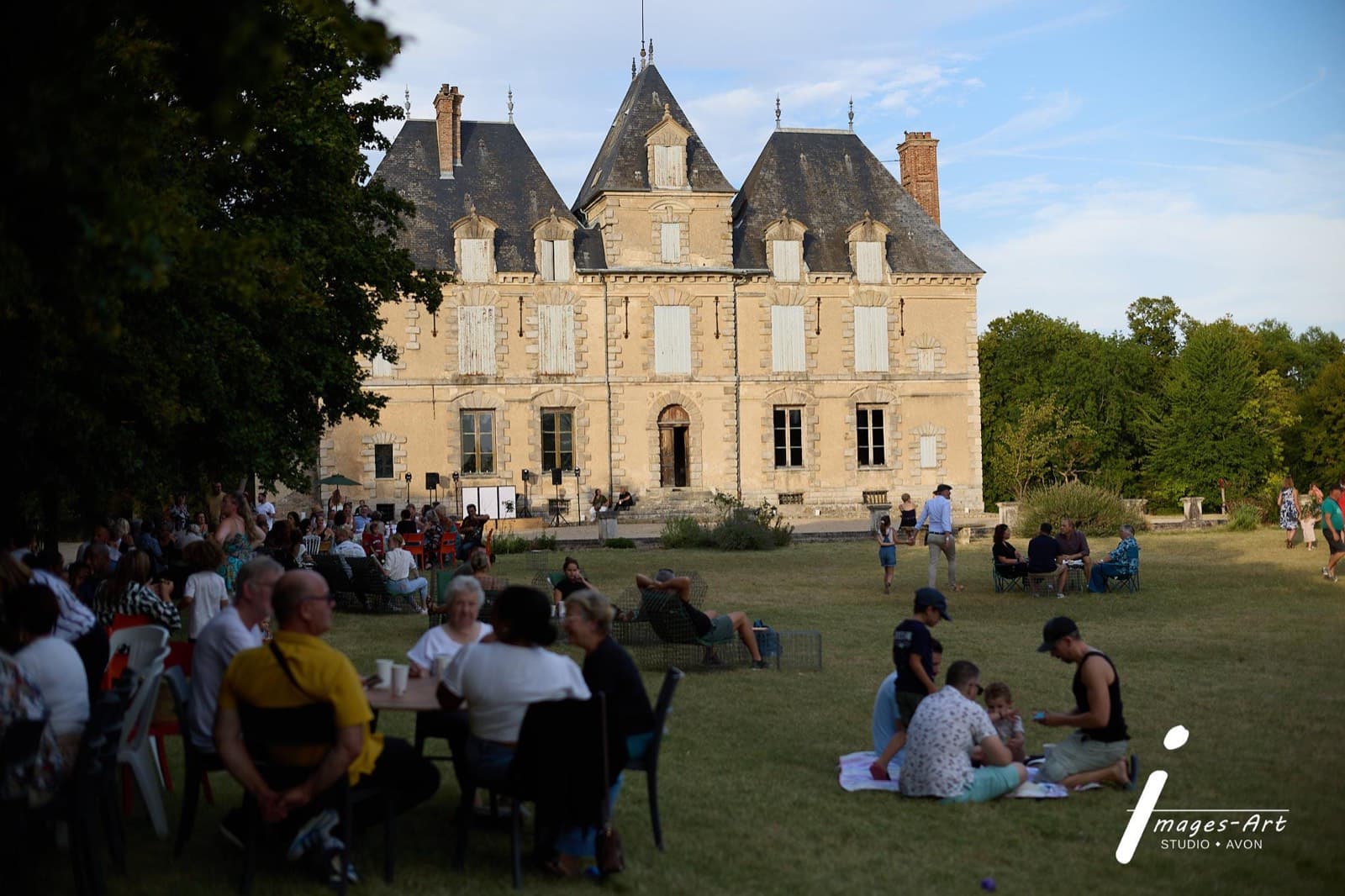 Public attablé sur la grande pelouse du château de Motteux lors d’une guinguette d’été en fin de journée
